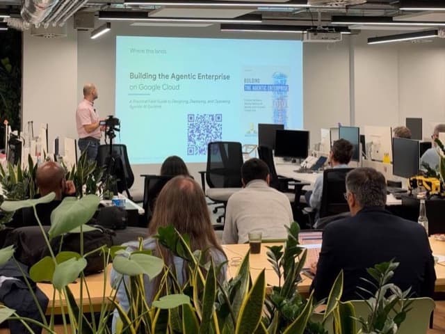 Jaroslav Pantsjoha at the front of the room beside a slide titled "Building the Agentic Enterprise on Google Cloud", showing the book cover and a QR code, as the audience watches.